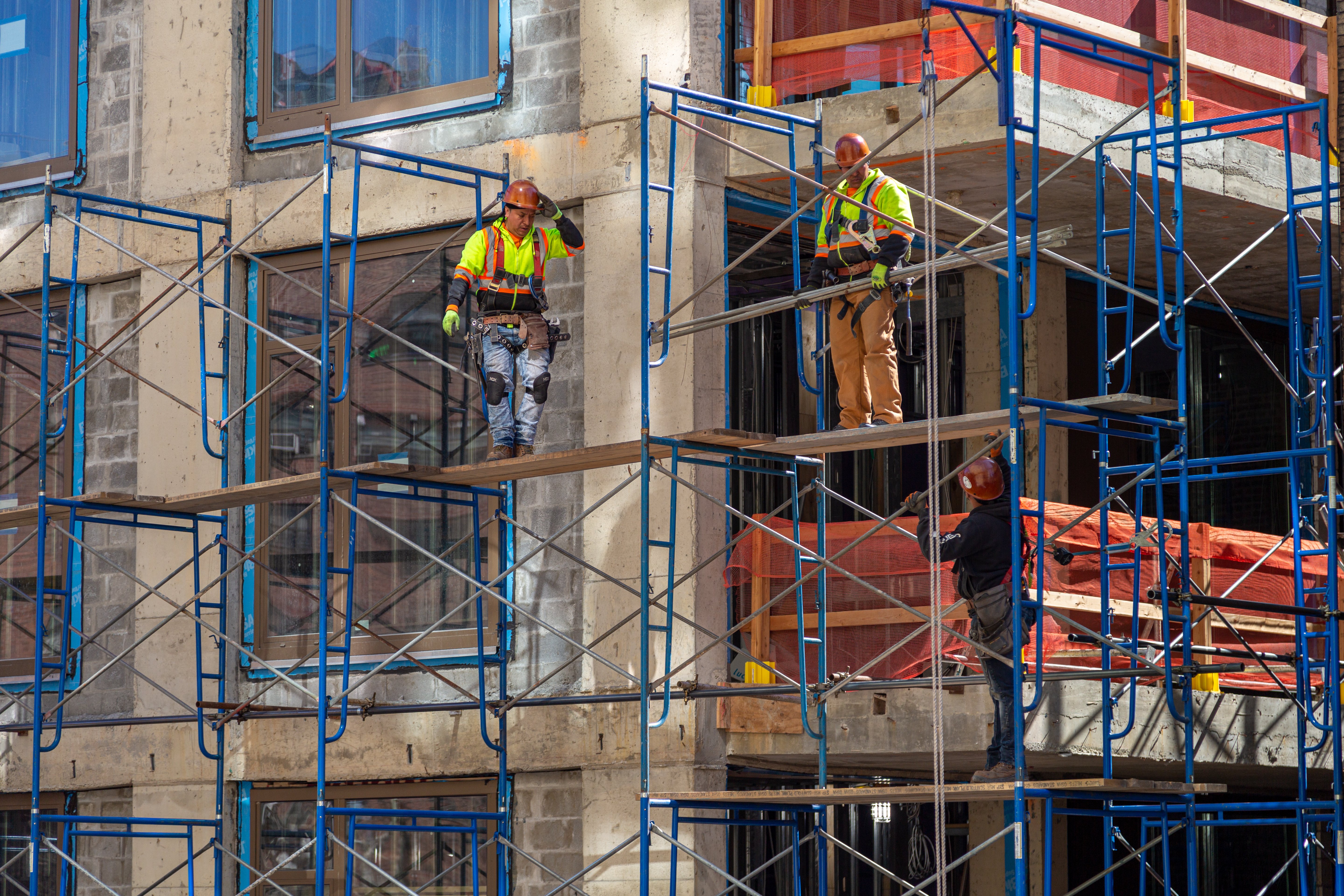 Construction workers at work on a skyscraper building renovation and construction site on a scaffold